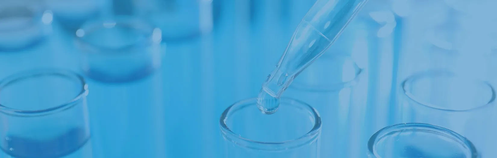 研究室でピペットを使い、試験容器に液体を滴下する様子。医療・バイオ研究を象徴するイメージ