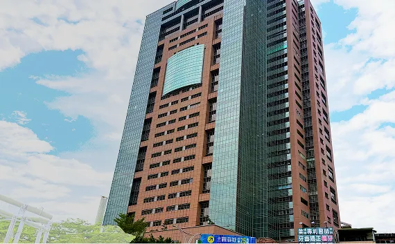 赤茶色の外壁と全面ガラス張りのパーツが組み合わさった、モダンなデザインの高層ビルの外観。