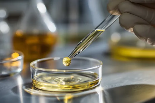 デスクの上にある図面や資料を囲み、ペンで指し示しながら共同作業を行うチームの手元。ビジネスウェアを着用した複数の人物が協力している様子。