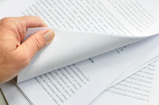 高層ビルの窓越しに広がる都市のパノラマビュー。手前には近現代的なガラス張りのビルの一部が写っている。