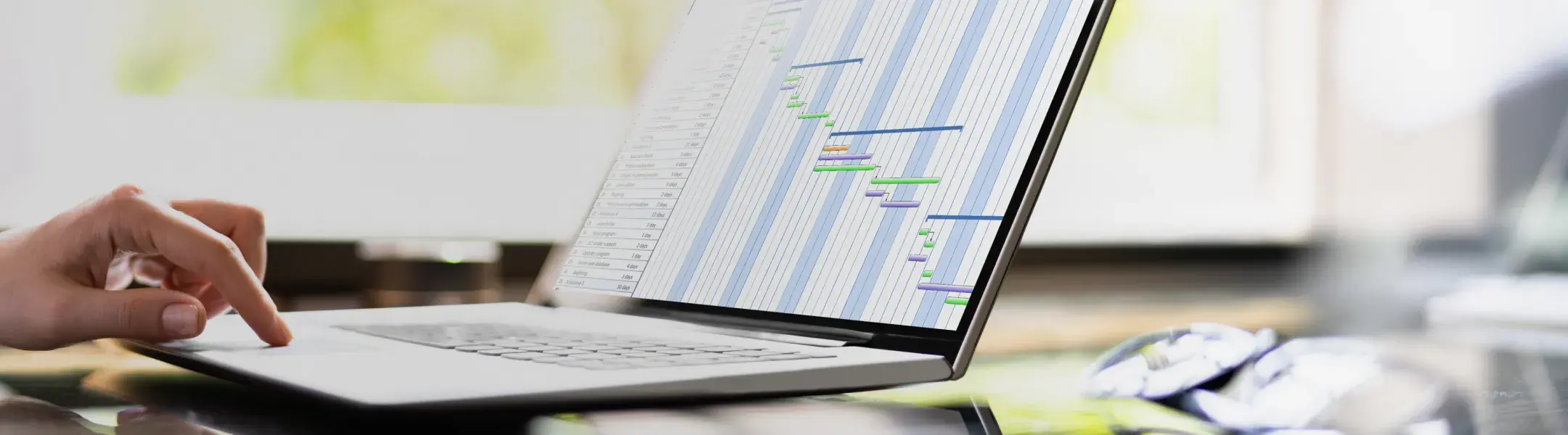 ノートパソコンの画面に表示されたガントチャートとプロジェクトを管理する手元